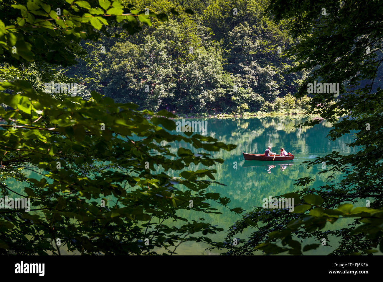 Pequeña embarcación de madera con dos personas en el lago del bosque Foto de stock