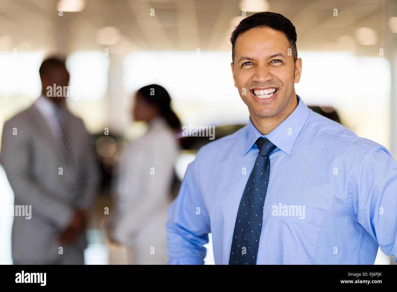 Feliz varón de mediana edad consultor de ventas de vehículos en showroom Foto de stock