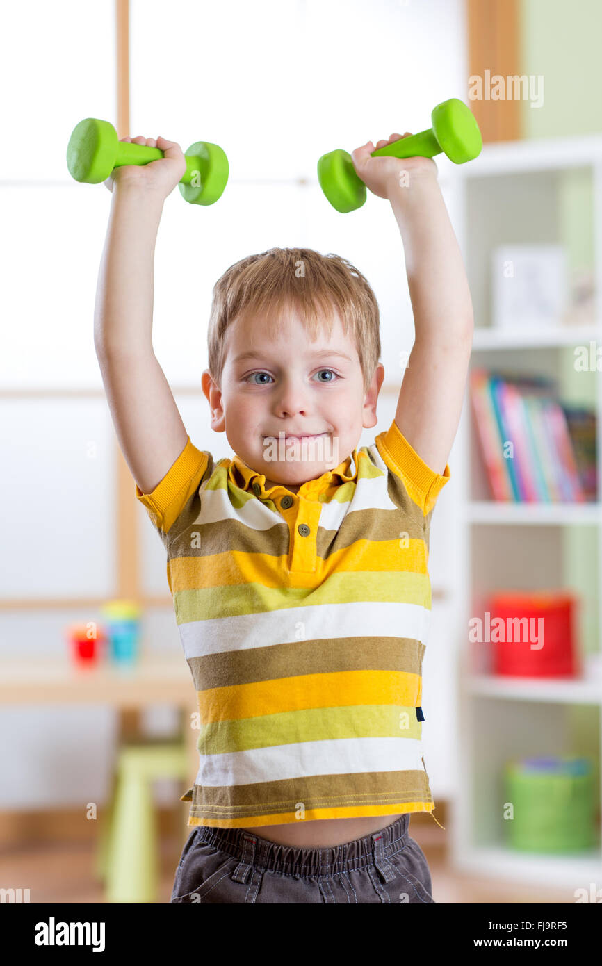 Niño sonriente muchachito el ejercicio con pesas. Concepto de deporte y vida sana. Foto de stock