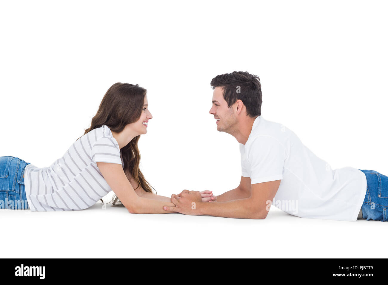 Pareja feliz tumbado en el suelo mirando el uno al otro y cogidos de la mano Foto de stock