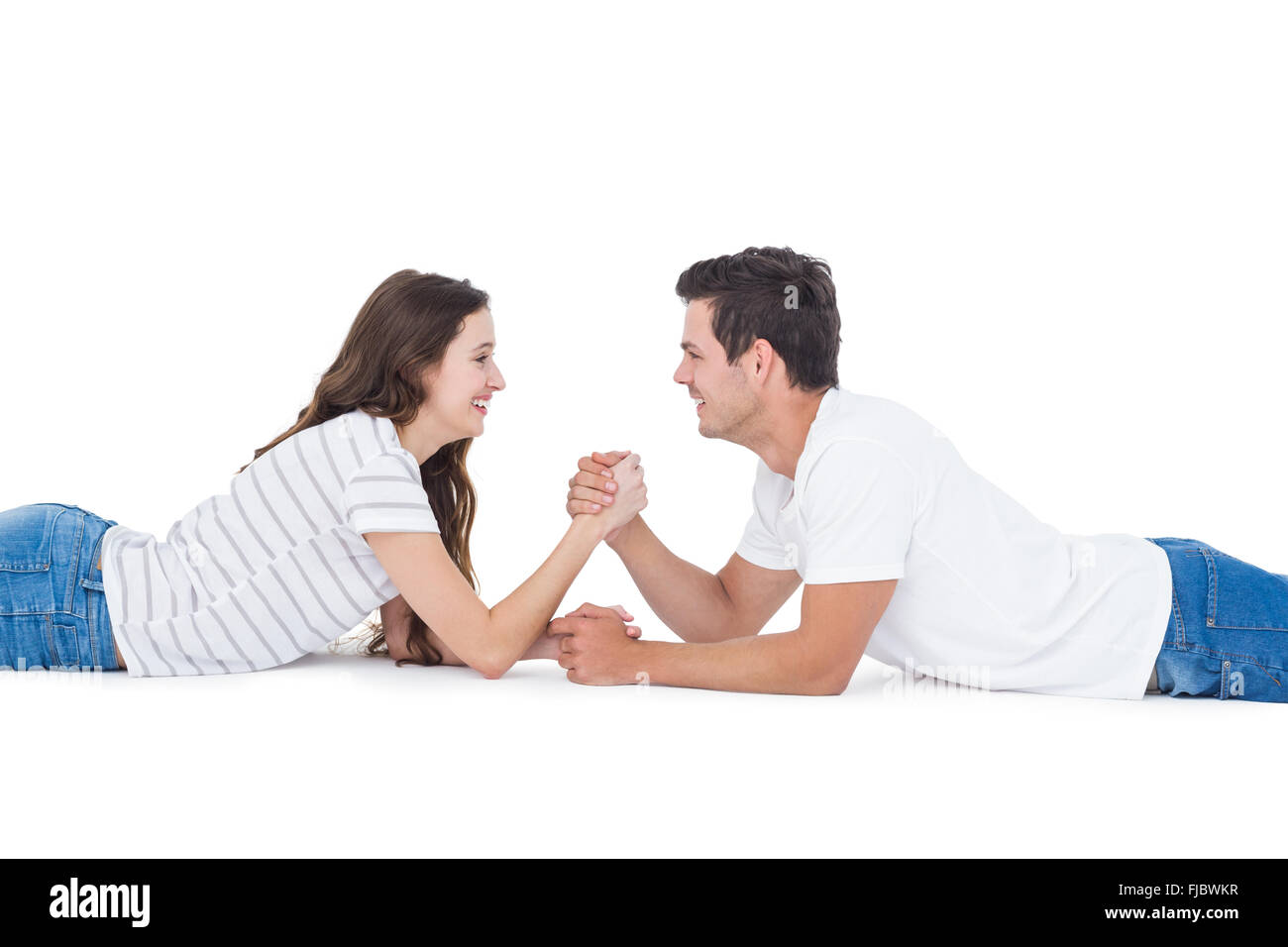 Pareja feliz tumbado en el suelo mirando el uno al otro y cogidos de la mano Foto de stock