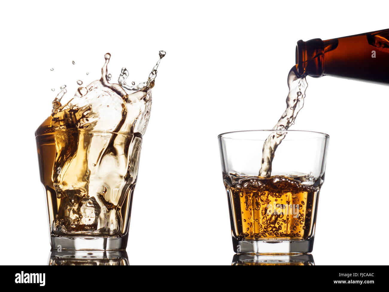 Verter el whisky en un vidrio claro, sobre fondo blanco. Foto de stock
