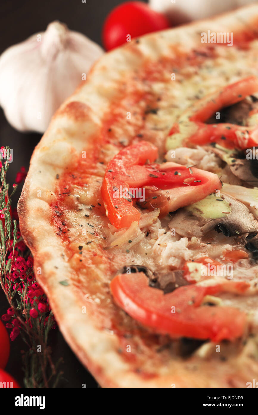 Pizza con tomates, setas y carne de pollo en posición vertical. Profundidad de campo Foto de stock