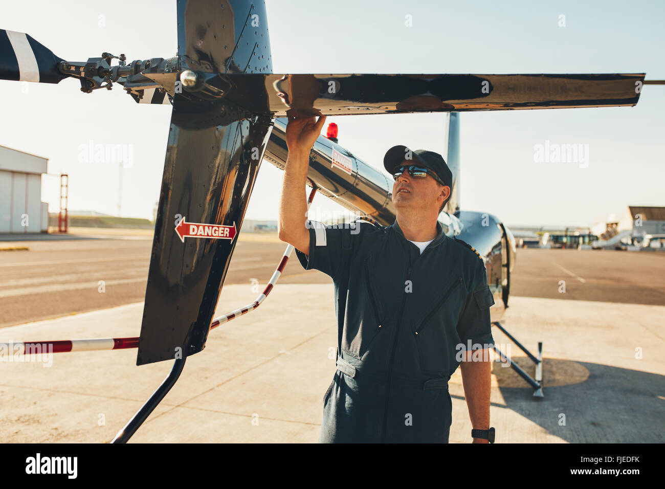 Hombres en uniforme de piloto de helicóptero de aleta trasera examinar. Inspección de pre vuelo por piloto en el aeropuerto. Foto de stock