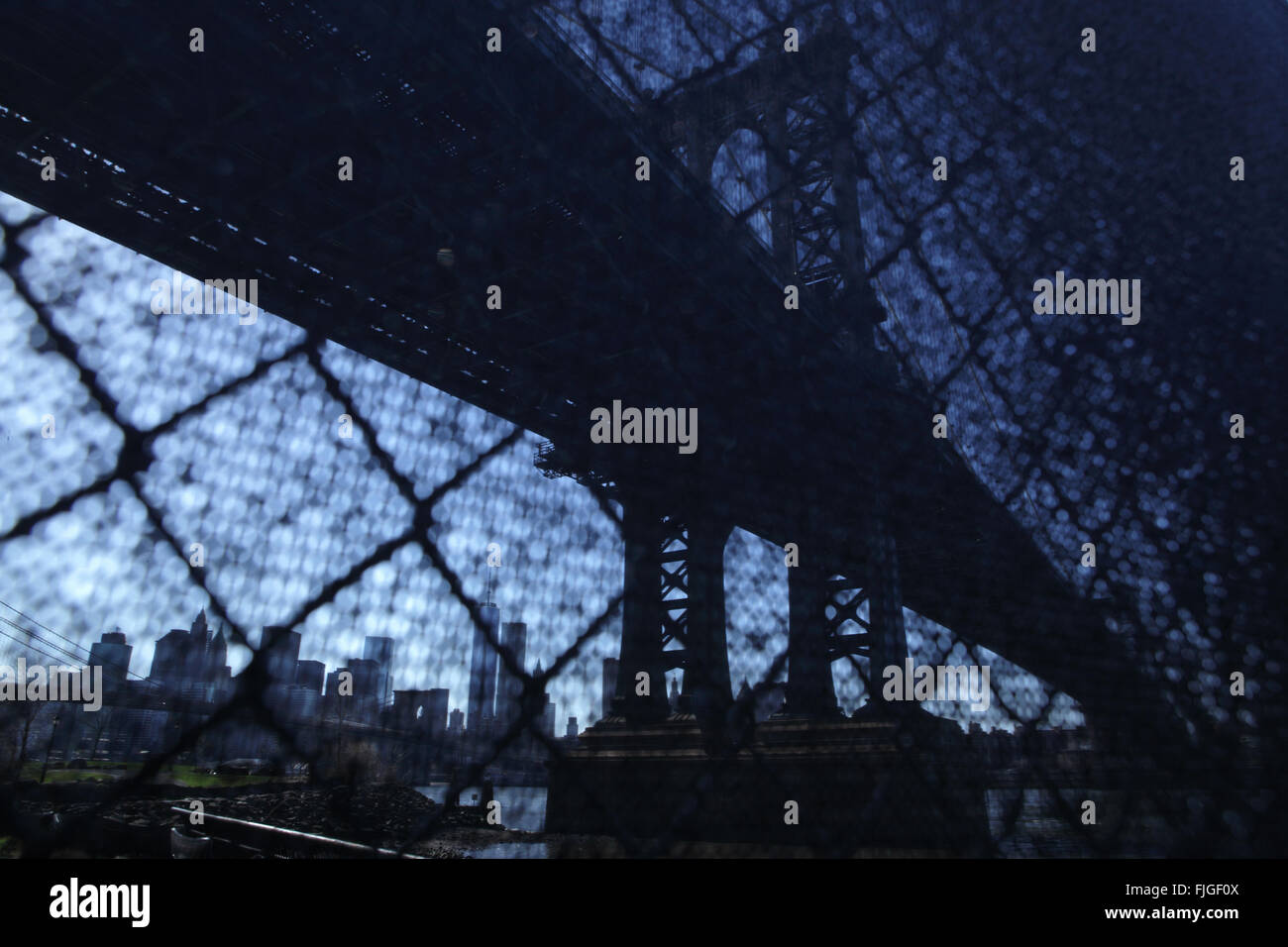 Distorsionada visión industrial de Manhattan Bridge waterfront fotografiado de la ciudad de Nueva York a través de una valla de alambre Foto de stock