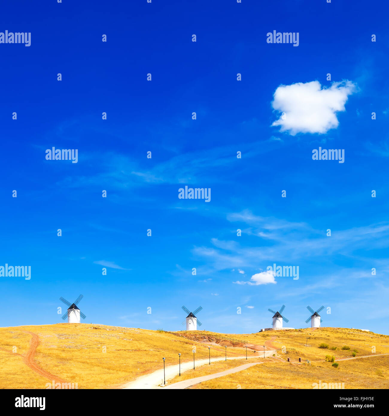 Cervantes Don Quijote rurales de molinos de viento, campos verdes, cielo azul y una pequeña nube en Consuegra. Castilla La Mancha, España, Europa Foto de stock