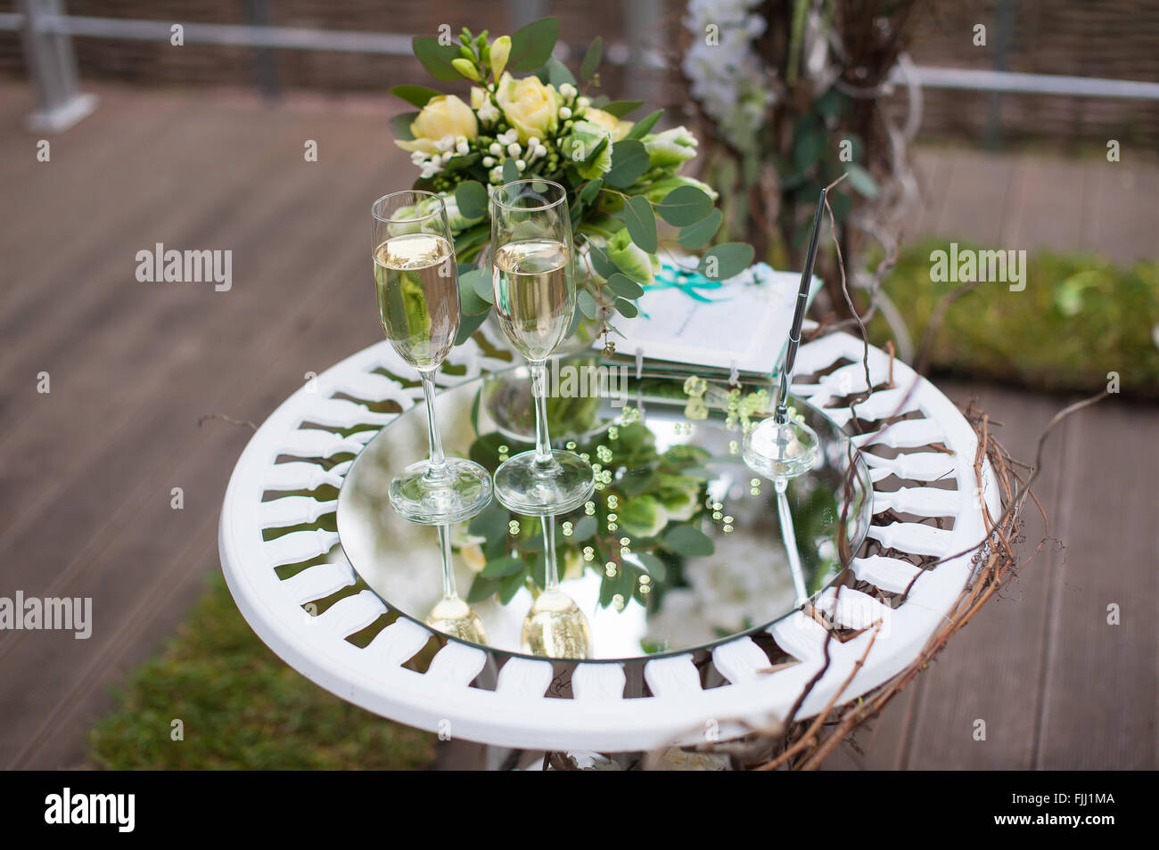Bouquet y copas de champaña en la superficie del espejo de la tabla en una boda al aire libre. Foto de stock