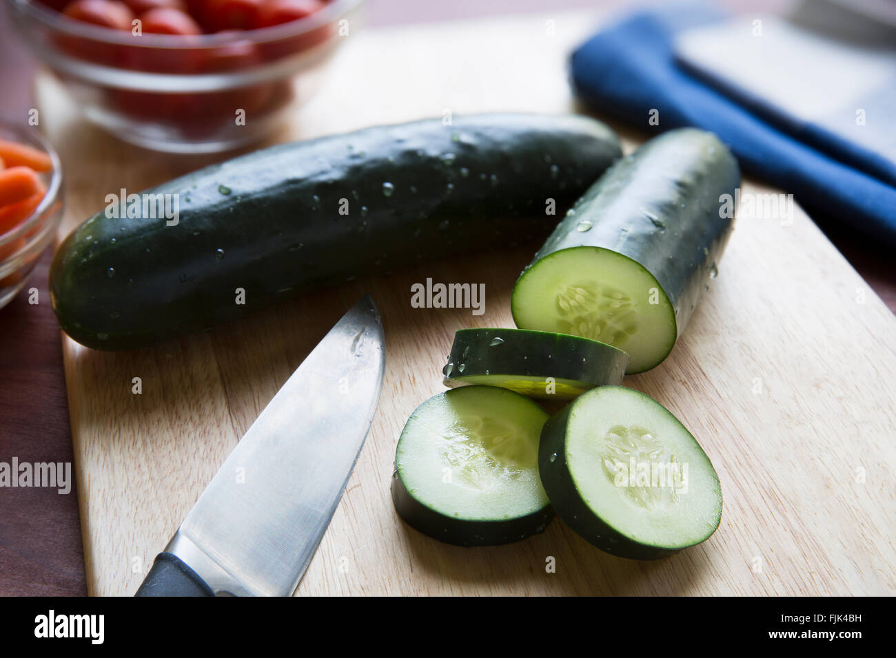 El pepino y el cuchillo sobre la tabla de cortar. Foto de stock
