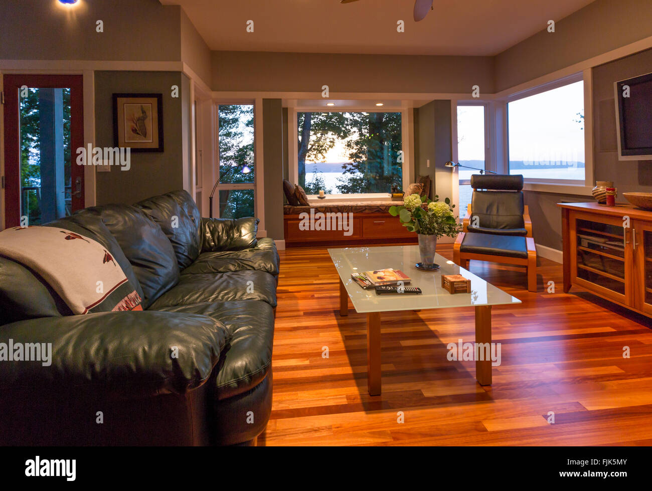 Casa lujo contemporáneo salón con pisos de madera, sofá de cuero, mesa de  café, asiento de ventana y ventanas con vistas al agua Fotografía de stock  - Alamy