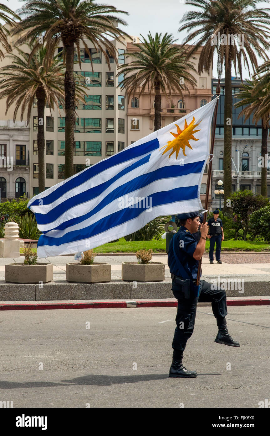 Oficial de policía marchando con la bandera en el desfile en Montevideo, Uruguay. Foto de stock