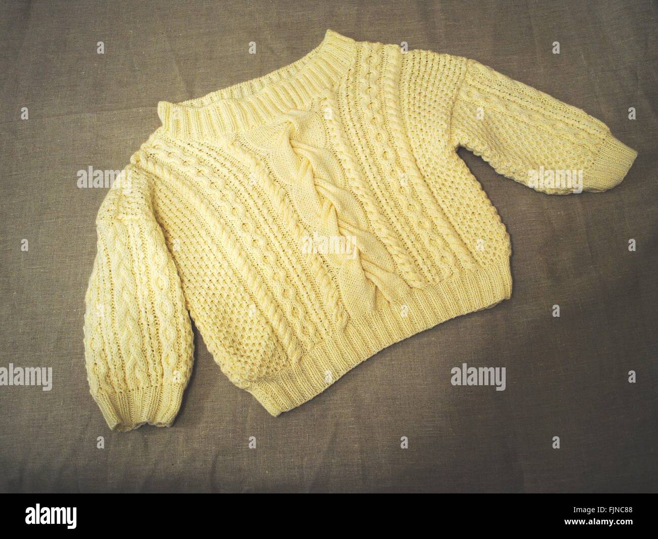 Un alto ángulo de visualización del suéter amarillo en la cama Foto de stock