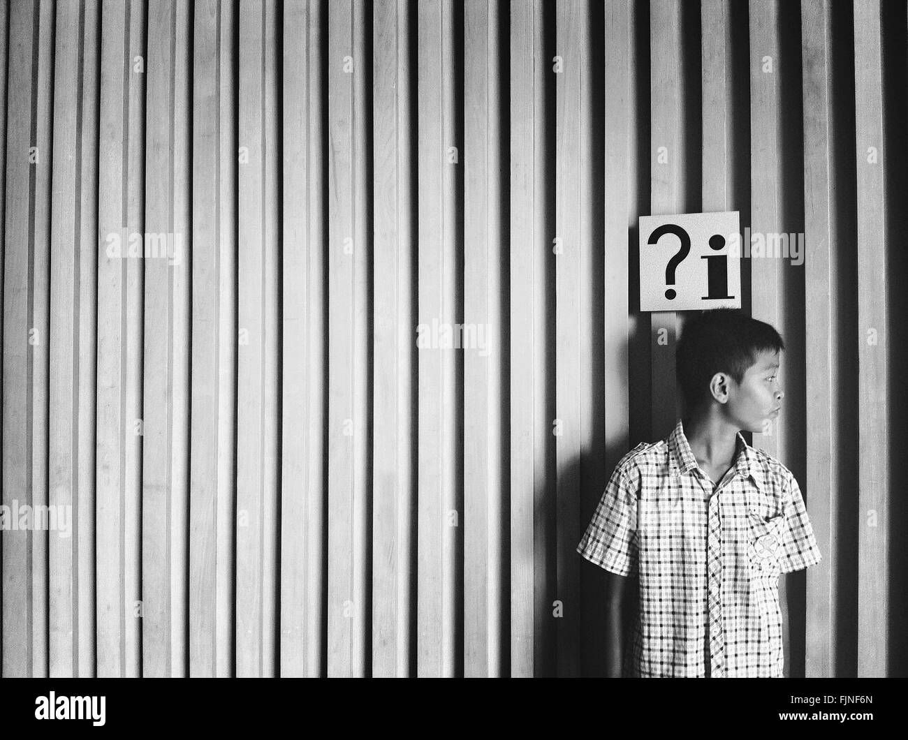 Vista frontal del muchacho de pie contra la pared Foto de stock