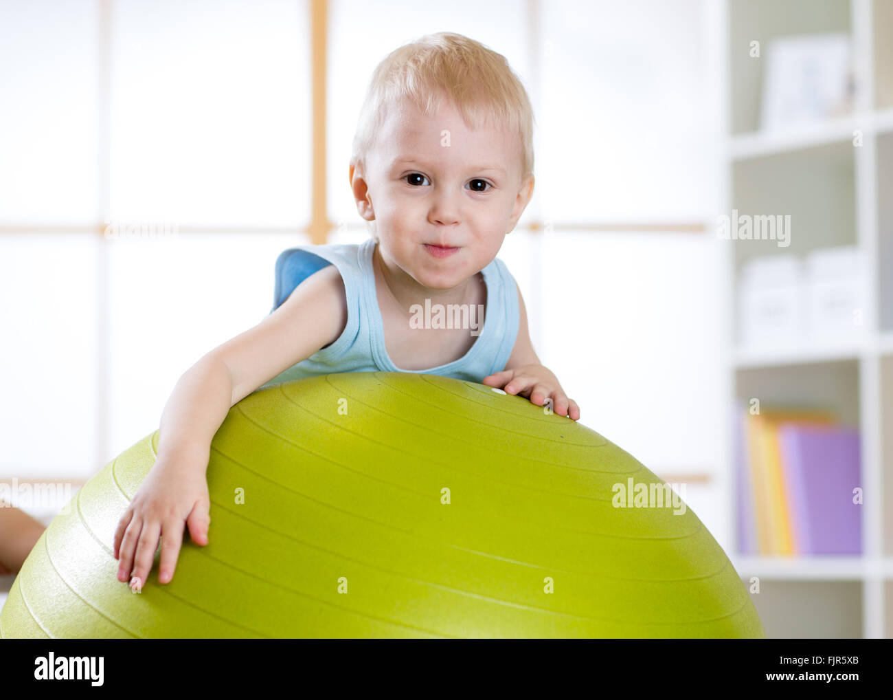 Niño chico jugando con fitball en interiores Foto de stock