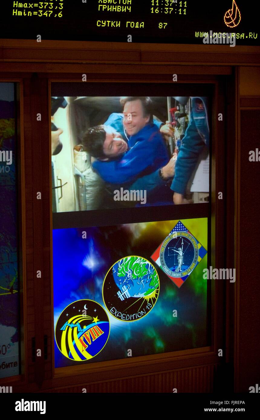 Monitores de vídeo muestran el cosmonauta ruso Yury Lonchakov, abrazando el astronauta Michael Barratt a bordo de la Estación Espacial Internacional durante la Expedición 19 docking, visto en el centro de control de misión ruso marzo 28, 2009 en Korolev, Rusia. Foto de stock