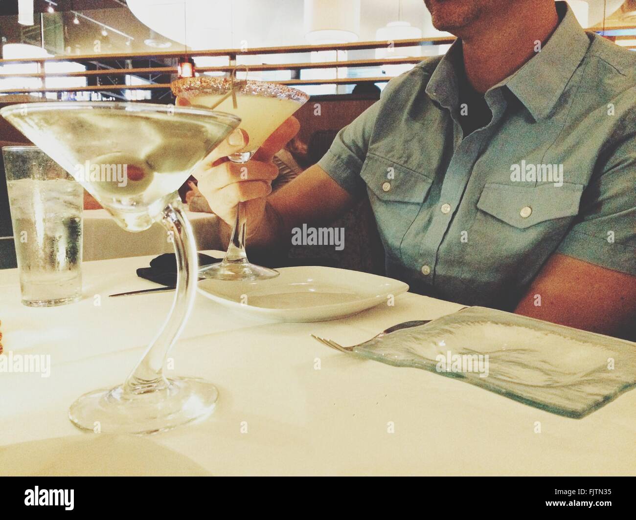 La mitad del torso de hombre con bebida en una mesa en el restaurante Foto de stock