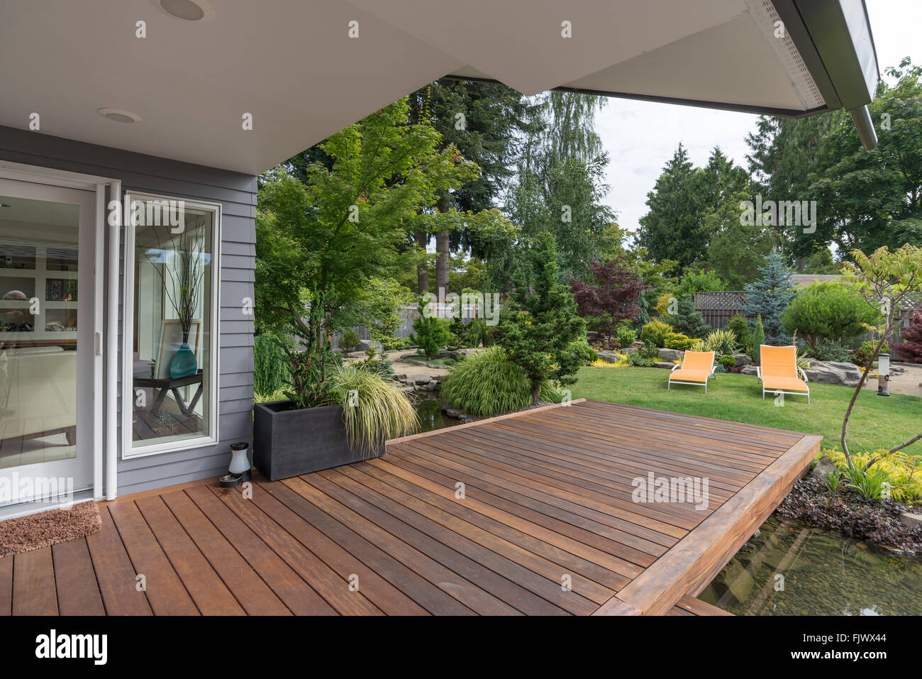 Una perspectiva de una casa del Noroeste del Pacífico contemporáneo con una baraja colmar una laguna que conduce a un par de lo moderno, de color amarillo Foto de stock