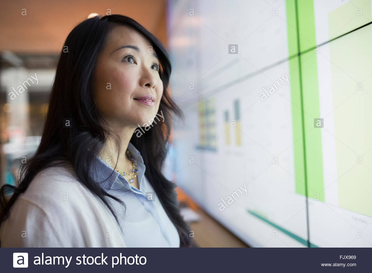 Curioso empresaria mirando hacia arriba en la pantalla de proyección. Foto de stock