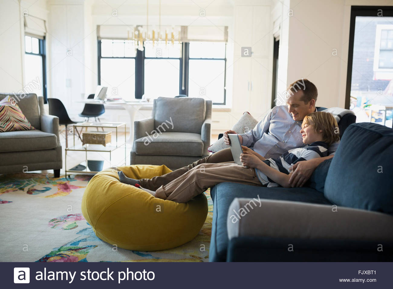 Padre hijo compartir sofá tableta digital Foto de stock