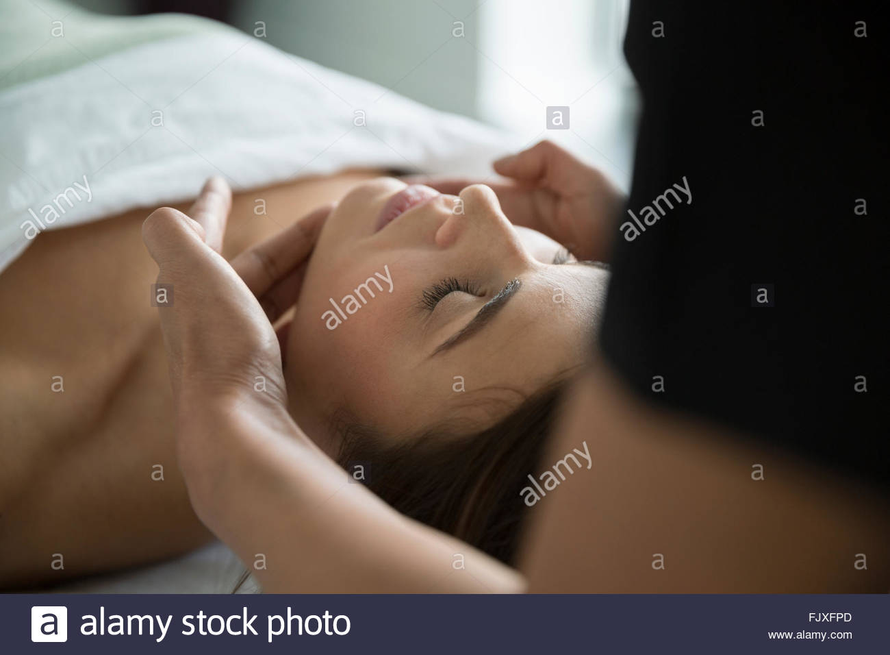 Mujer serena con los ojos cerrados recibiendo facial spa Foto de stock