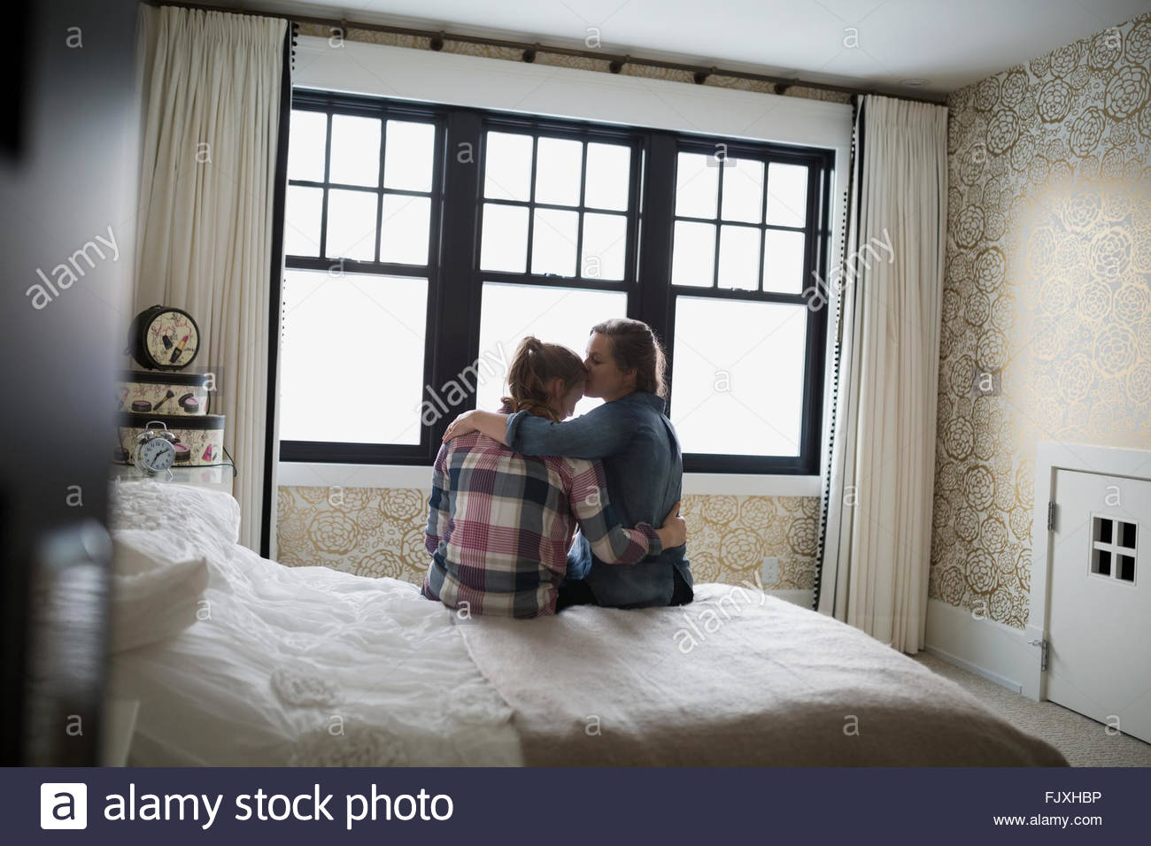 Abrazos y besos madre hija adolescente en dormitorio Foto de stock