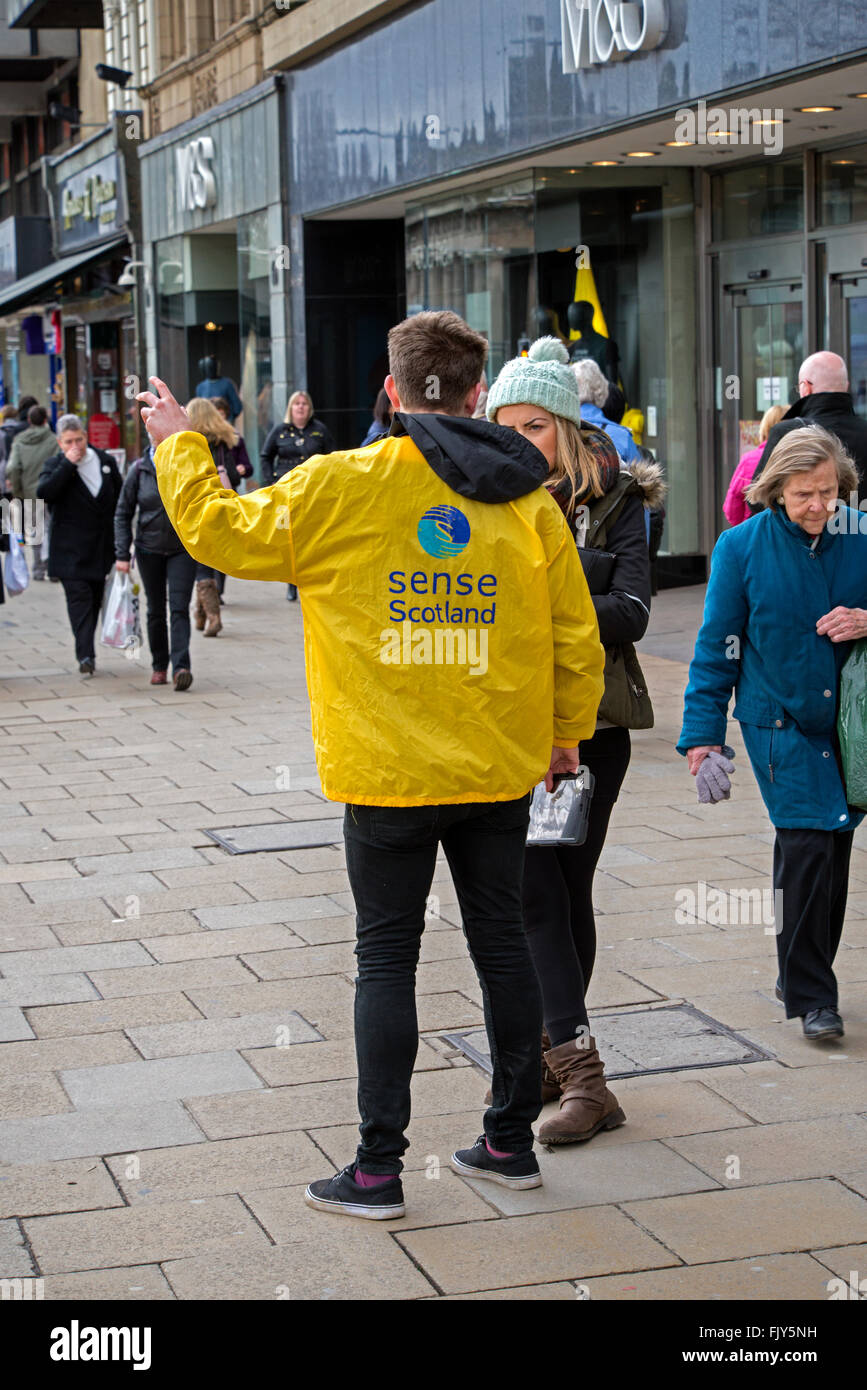 Recaudador de fondos de caridad o chugger sentido para Escocia hablando con una joven mujer en Princes Street, Edimburgo, Escocia, Reino Unido. Foto de stock