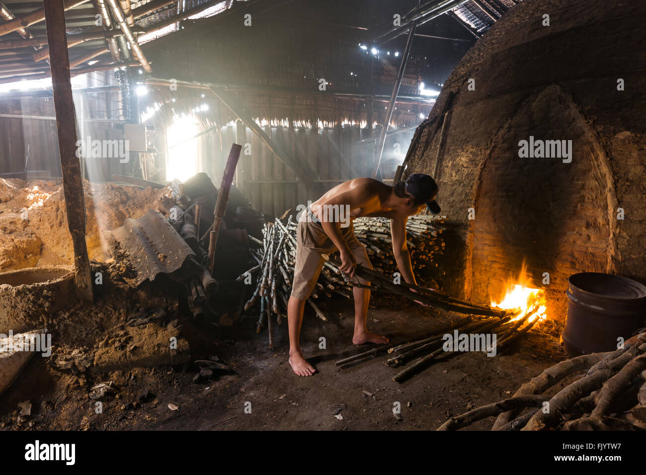 Un trabajador de carbón en el trabajo sobre un montón de lenta combustión de madera fábrica de carbón Foto de stock