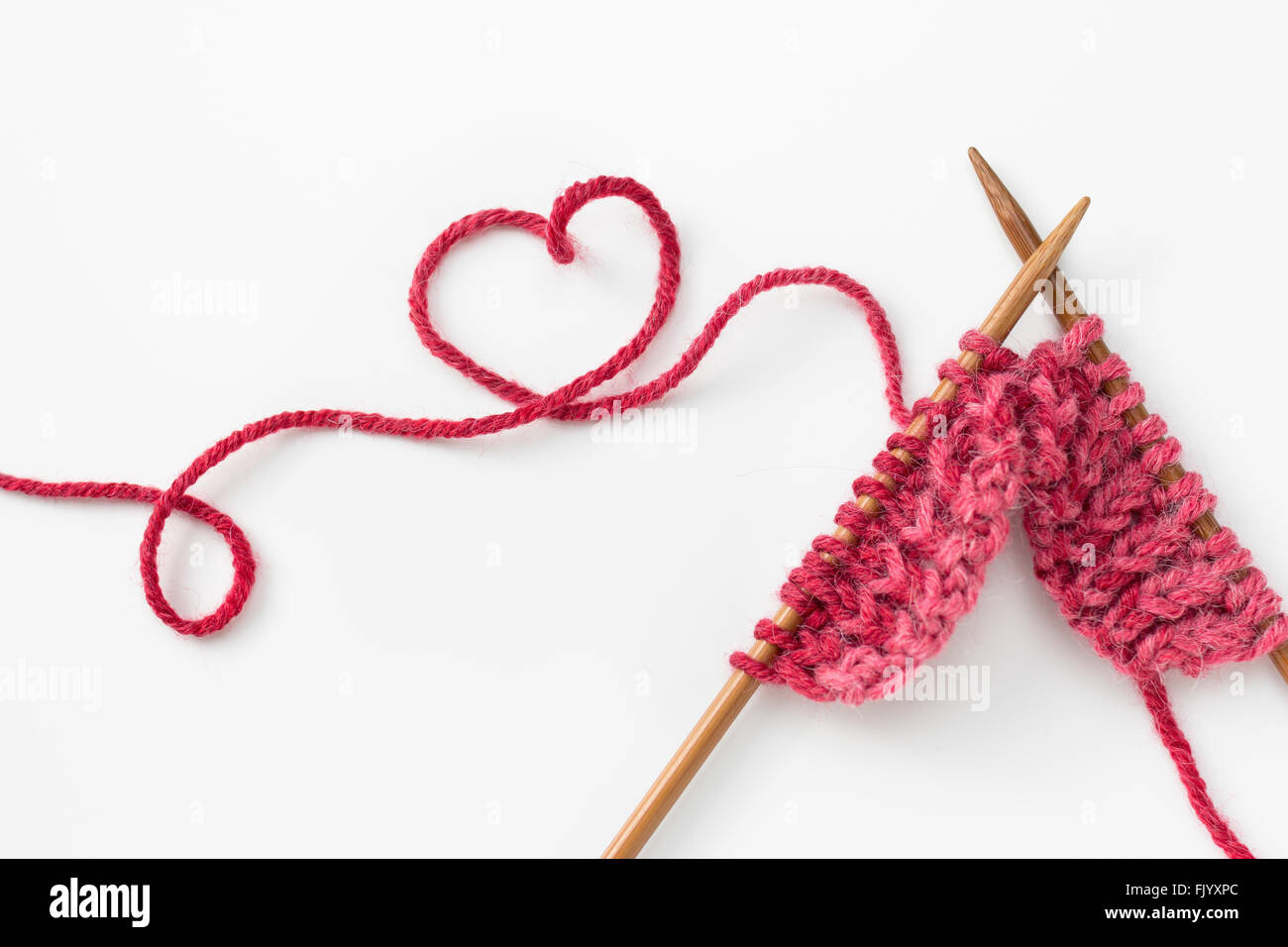 Proyecto de tejer incompleta con hilados de lana en forma de corazón Foto de stock