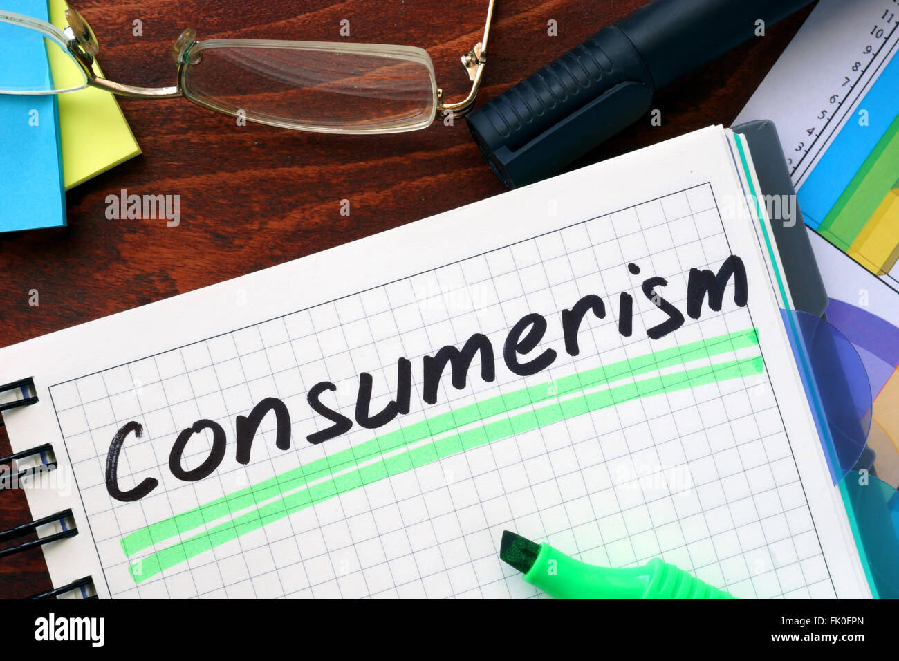 El consumismo concepto escrito en un cuaderno sobre una mesa de madera. Foto de stock