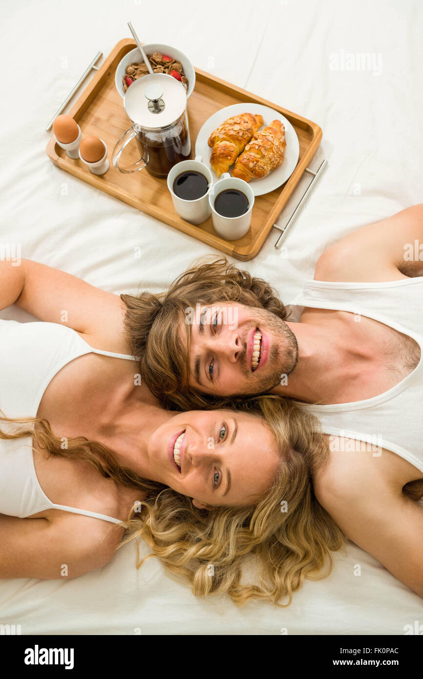 Linda pareja acostado en la cama junto a una bandeja con el desayuno Foto de stock