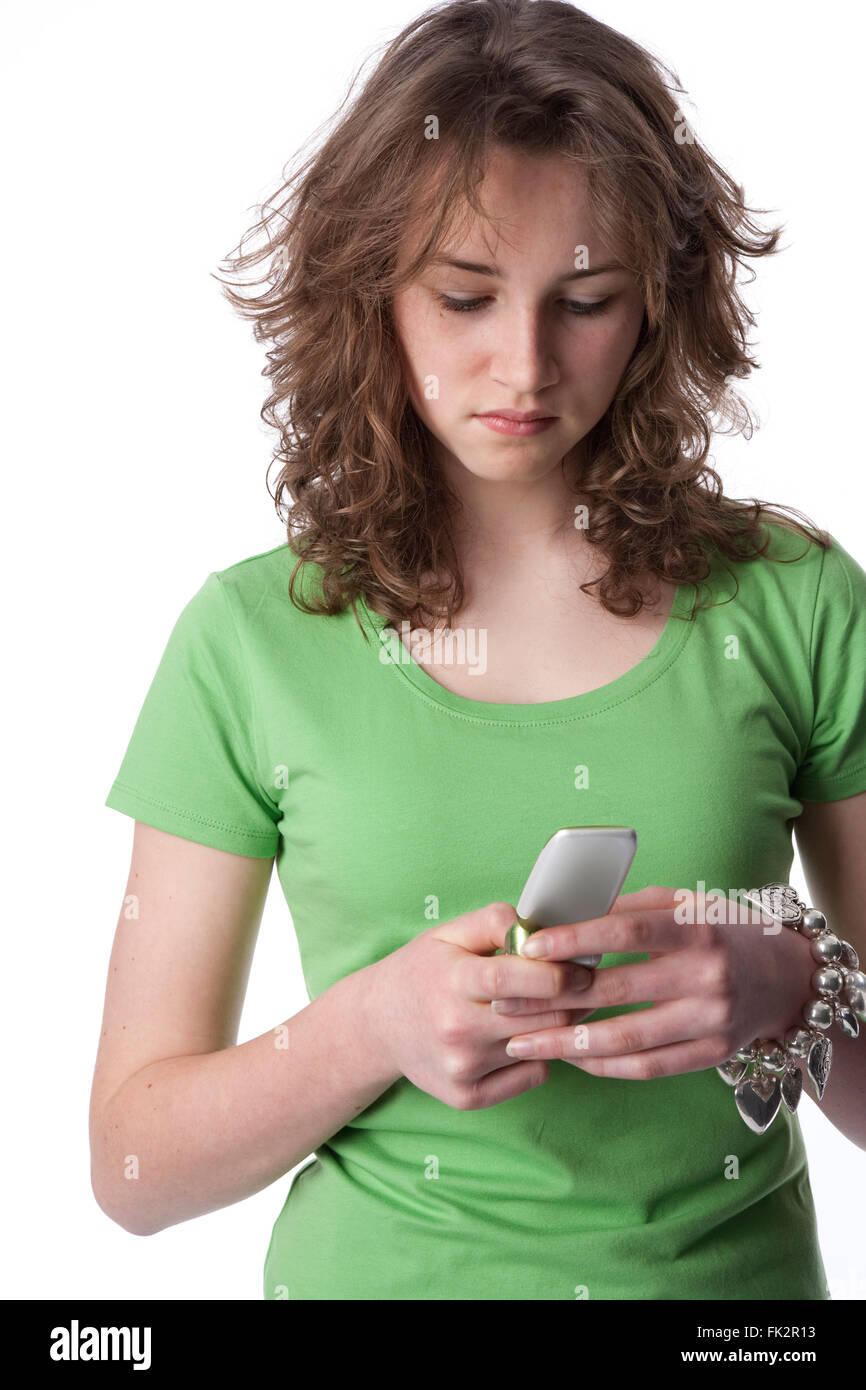 Adolescente es la lectura de un mensaje en su teléfono móvil sobre fondo blanco. Foto de stock