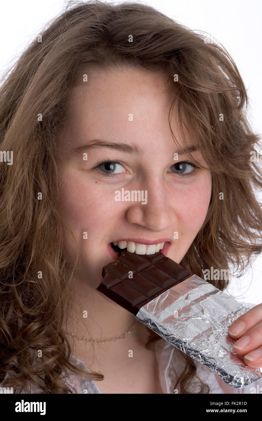 Adolescente comiendo chocolate sobre fondo blanco. Foto de stock