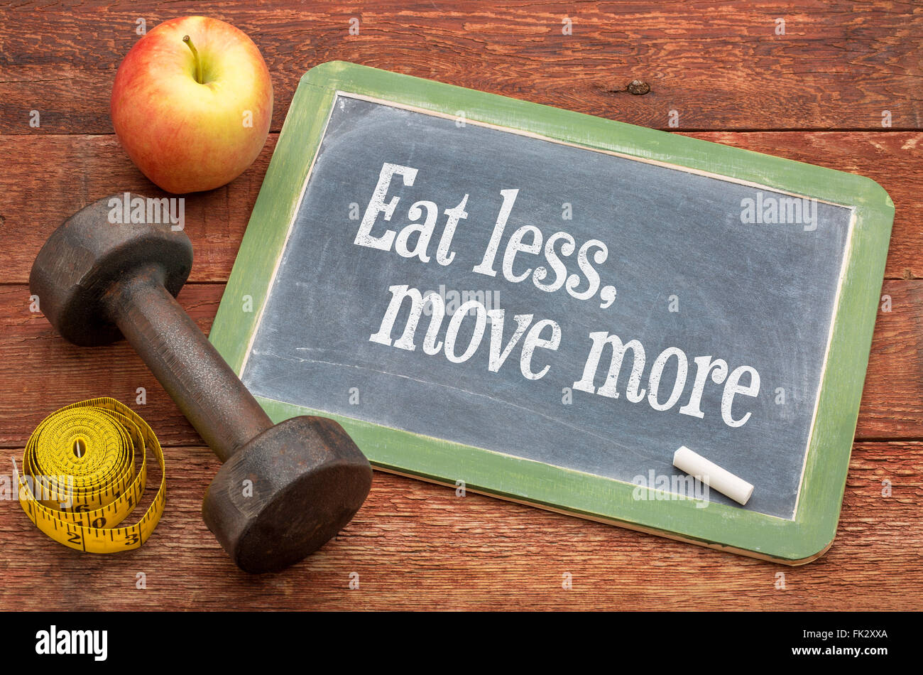 Comer menos y moverse más fitness y la vida saludable concepto - pizarra pizarra signo contra capeado el granero de madera pintados en rojo Foto de stock