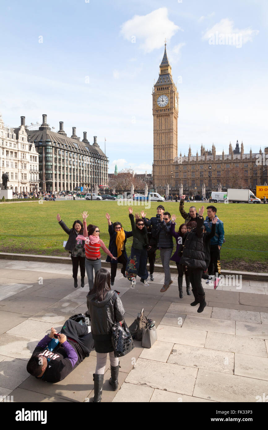 Un grupo de turistas chinos en Londres saltar en el aire delante del Big Ben, Parliament Square, Londres, Gran Bretaña. Foto de stock
