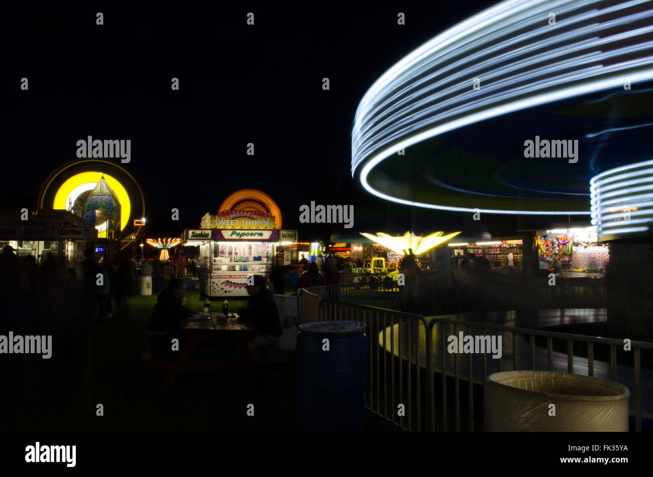 Feria rural de carnaval por la noche con luces y paseos en acción Foto de stock