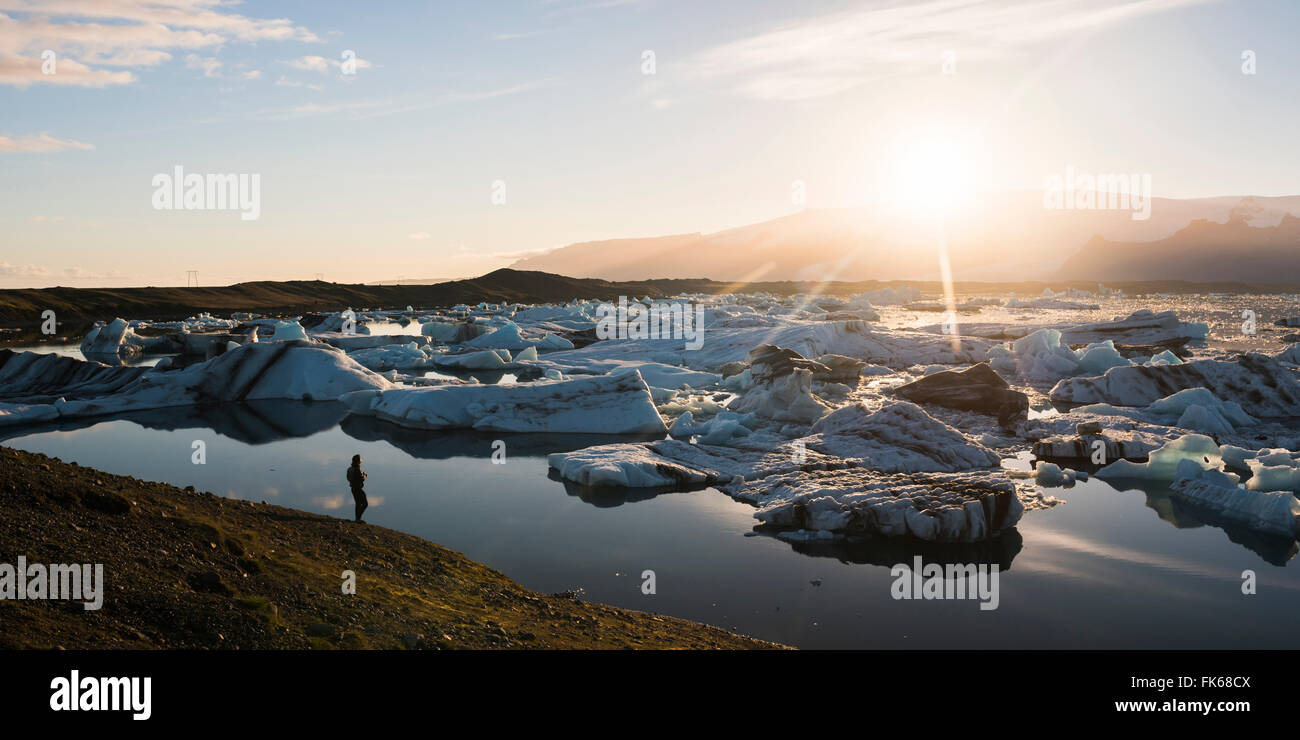 Turista en la Laguna glaciar Jokulsarlon al atardecer, Sureste de Islandia, Islandia, las regiones polares Foto de stock