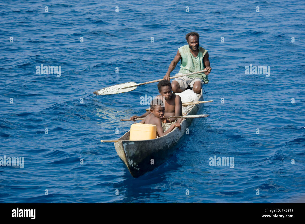 Familia Papúes en su canoa. Foto de stock