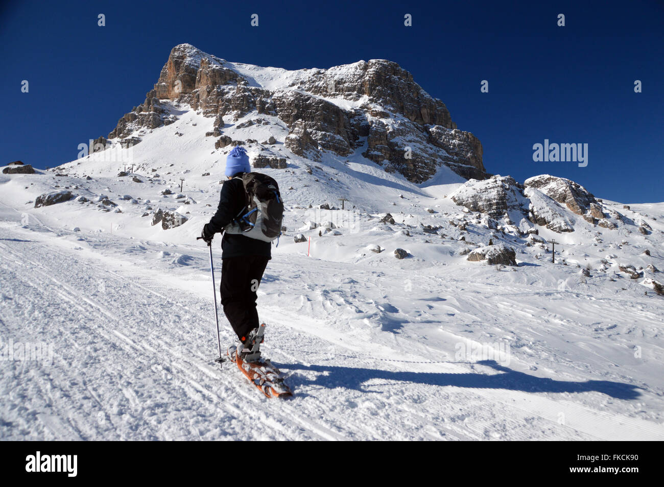 Una solitaria mujer sola raquetas de nieve cuesta arriba hacia el Refugio Averau y monte Averau Foto de stock