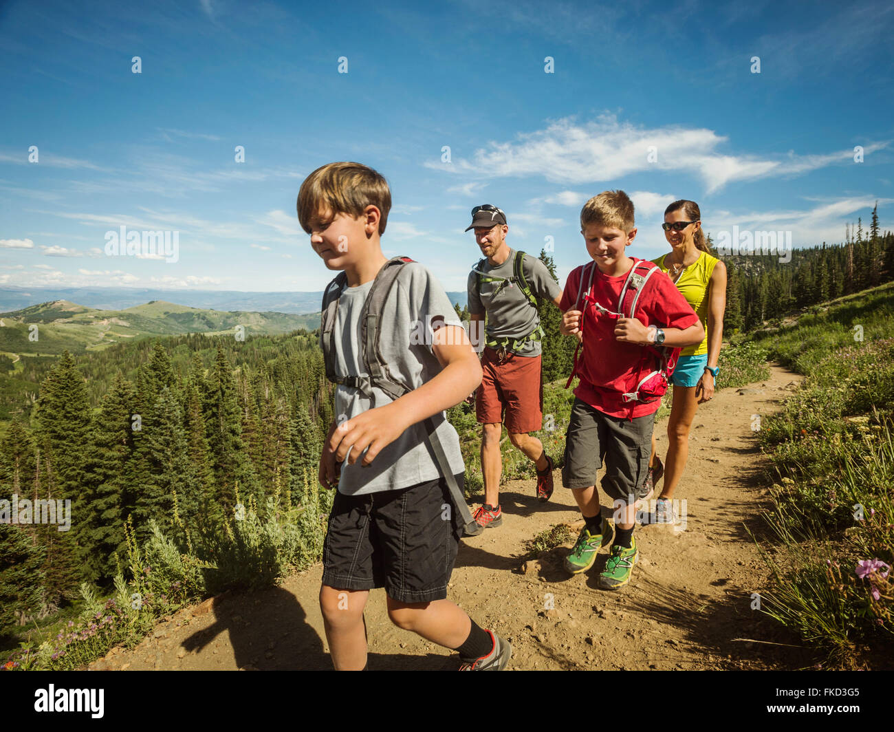 Familia con dos niños (10-11, 12-13) el senderismo en las montañas Foto de stock