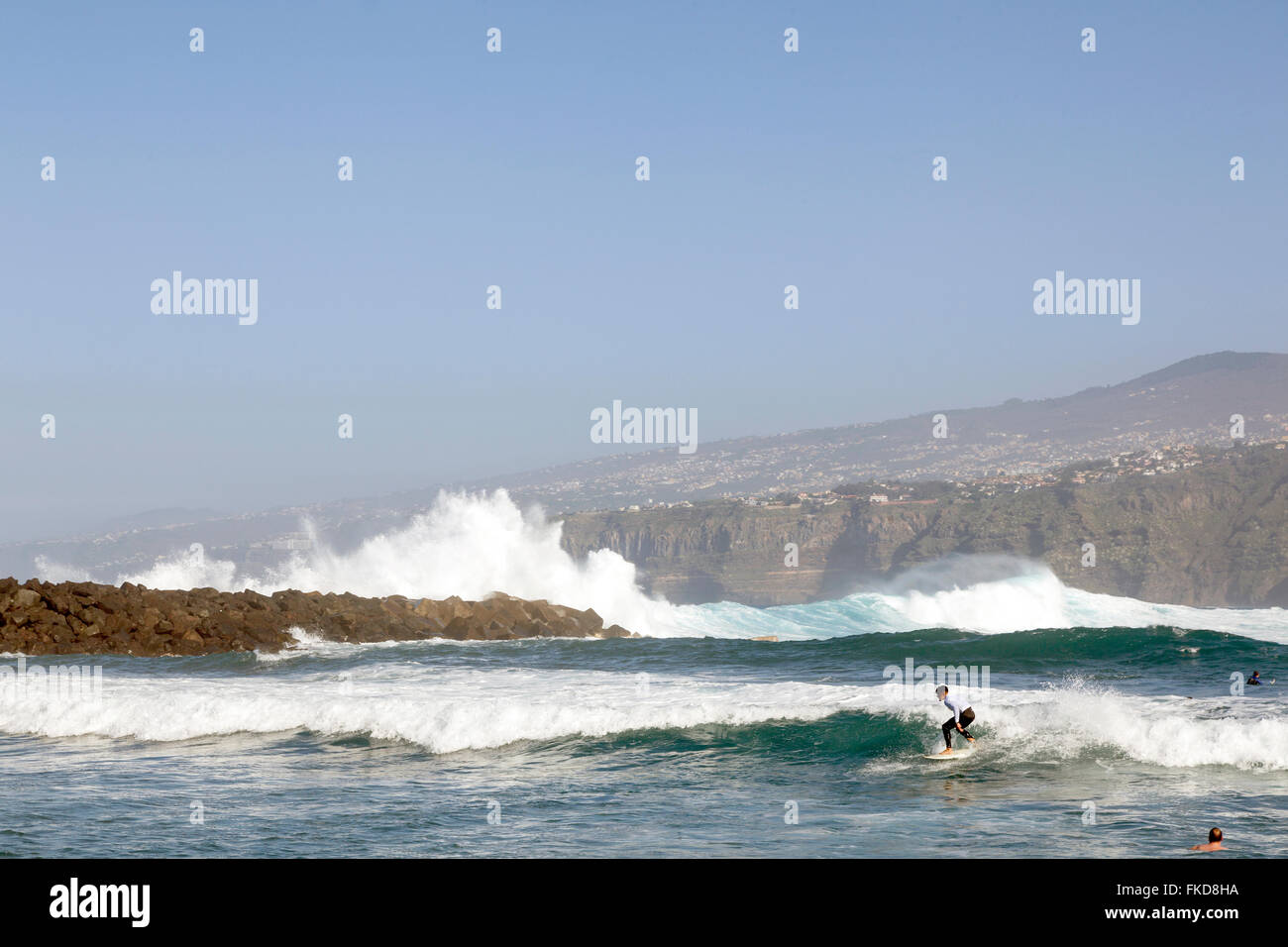 Hombre surf en las olas de puerto de la cruz en Tenerife con el paisaje en  el fondo Fotografía de stock - Alamy