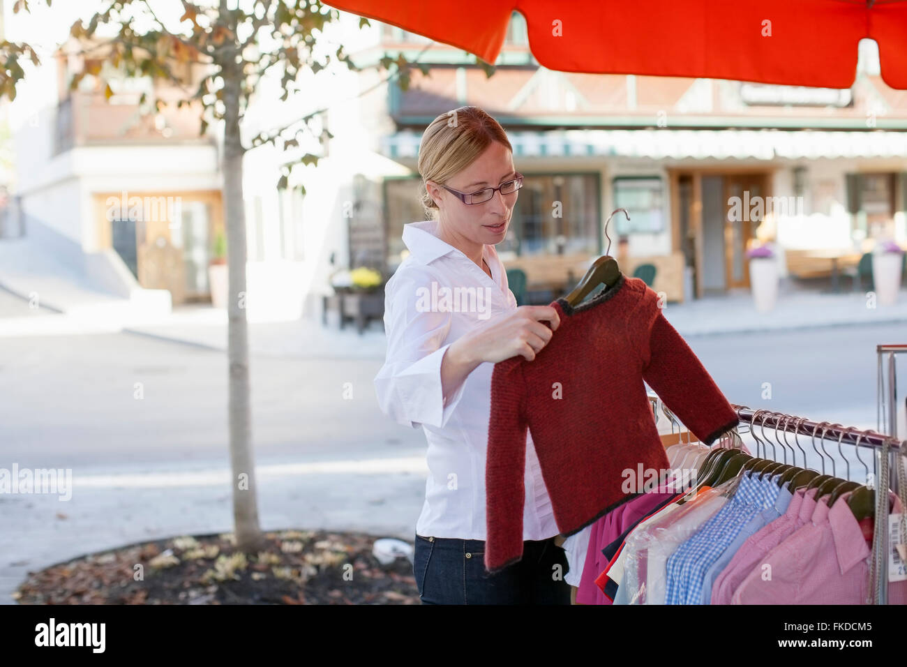 Mujer toma suéter de perchero Foto de stock