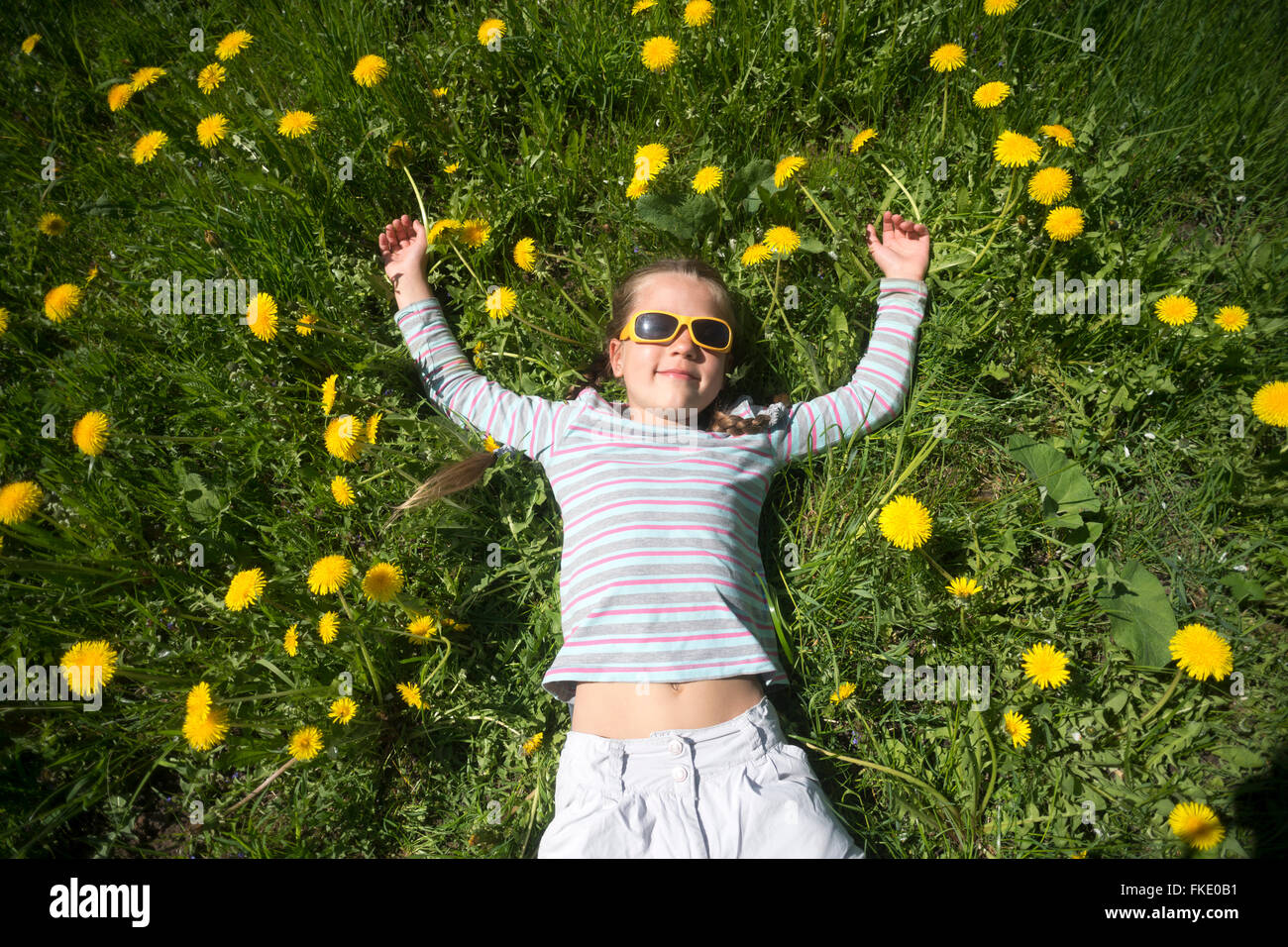 Chica goza de un clima soleado en primavera tendido entre muchas flores jaramago amarillo Foto de stock