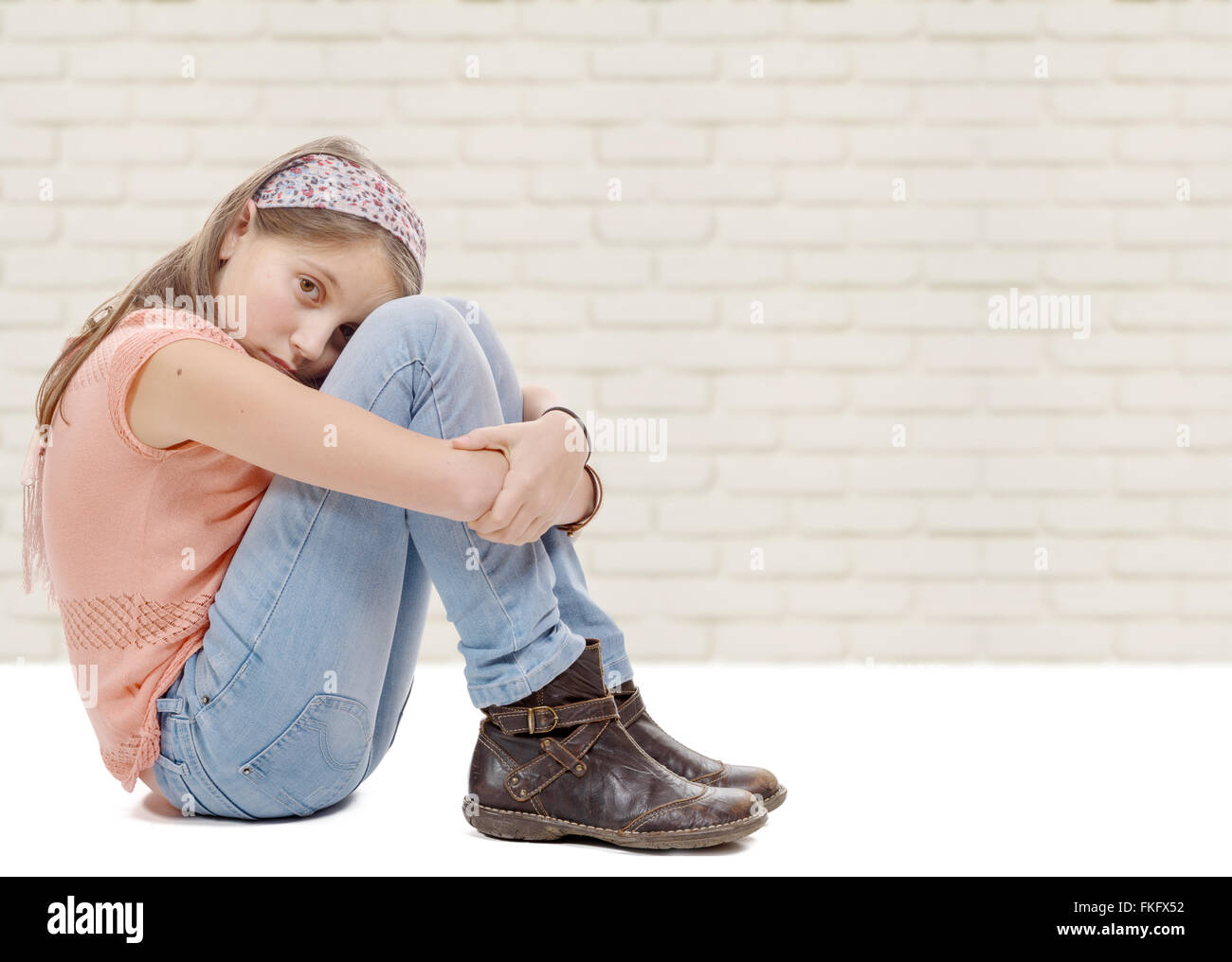 Una pre-teen girl triste n está sentado en el suelo Foto de stock