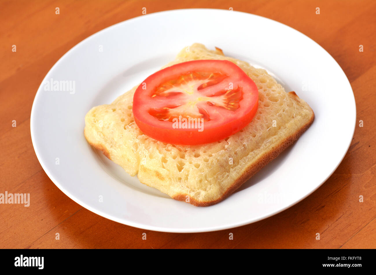 Forma cuadrada con mantequilla crumpet inglés con rodaja de tomate.Es