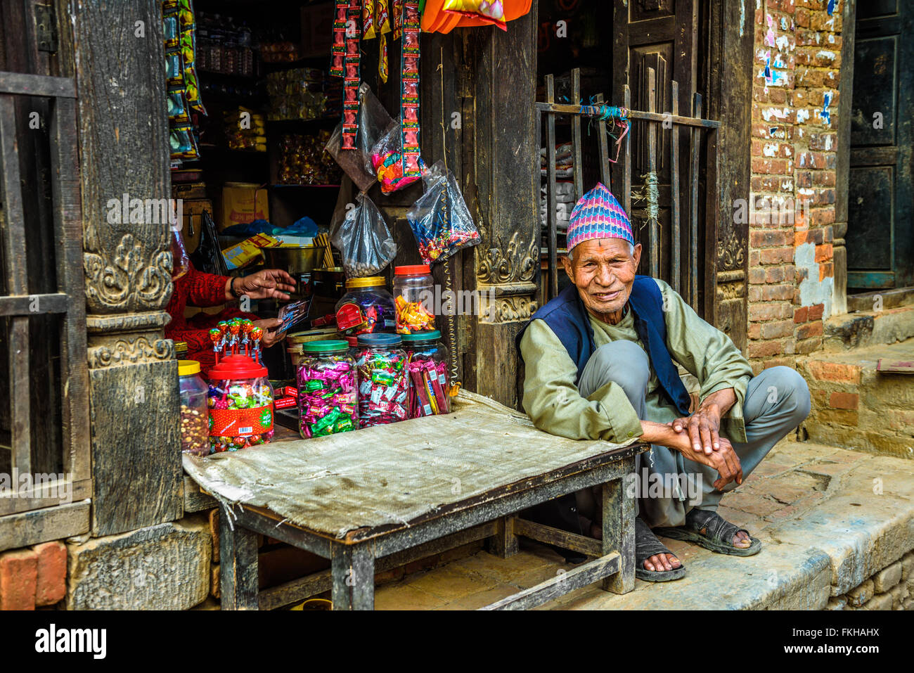 Viejo hombre de Nepal y su esposa venden sus productos en su tienda. Foto de stock