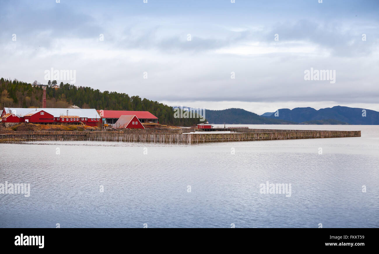 Piscifactoría noruego tradicional con casas de madera roja en el Seacoast Foto de stock
