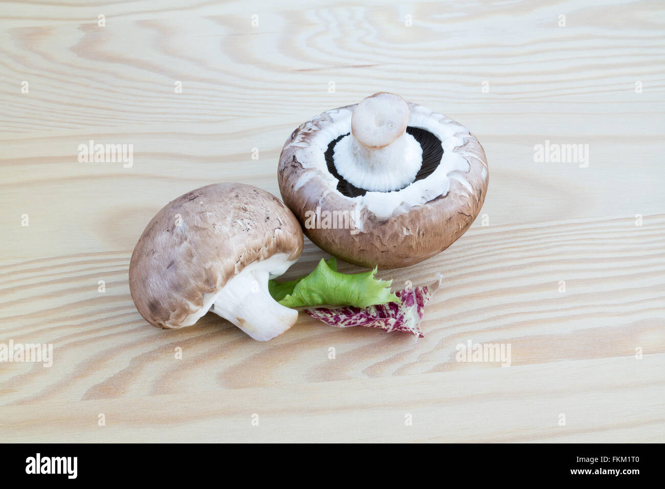 Dos castaños con algunos champiñones lechuga verde y rojo sobre una tabla de cortar de madera Foto de stock