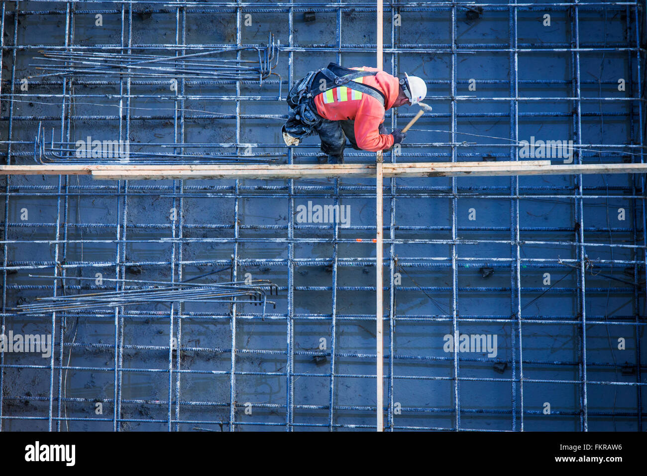 Trabajador caucásico clavando tablones en sitio en construcción Foto de stock
