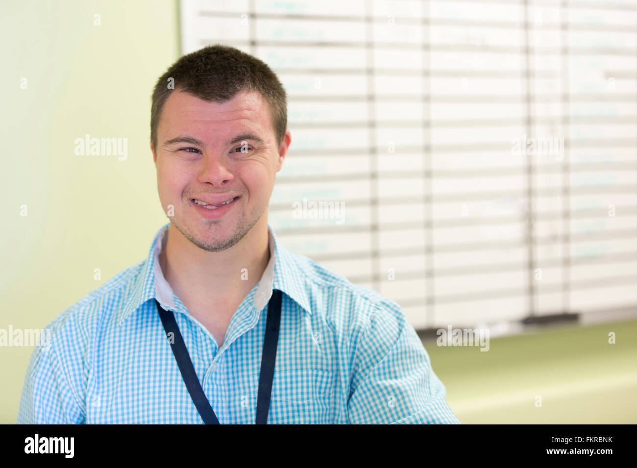 Hombre caucásico con síndrome de Down sonriendo en la oficina Foto de stock