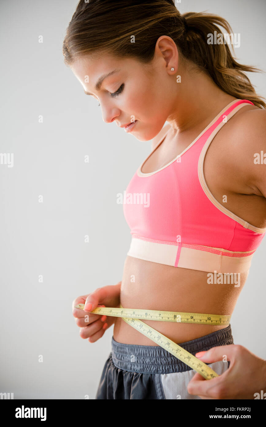 Mujer de raza mixta midiendo su cintura Foto de stock
