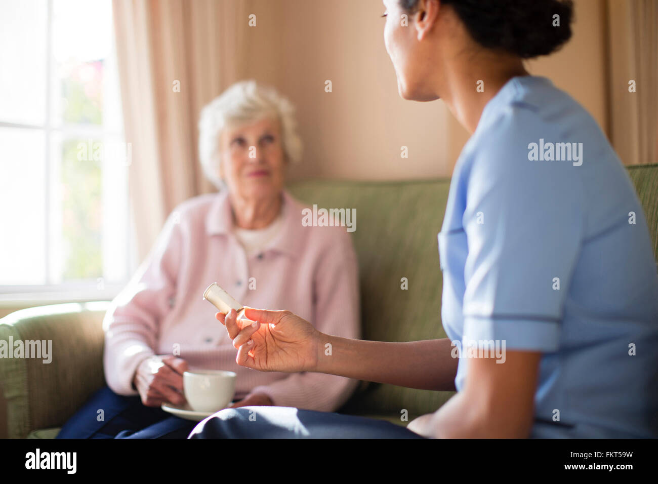 La enfermera y el paciente beber té en el sofá Foto de stock
